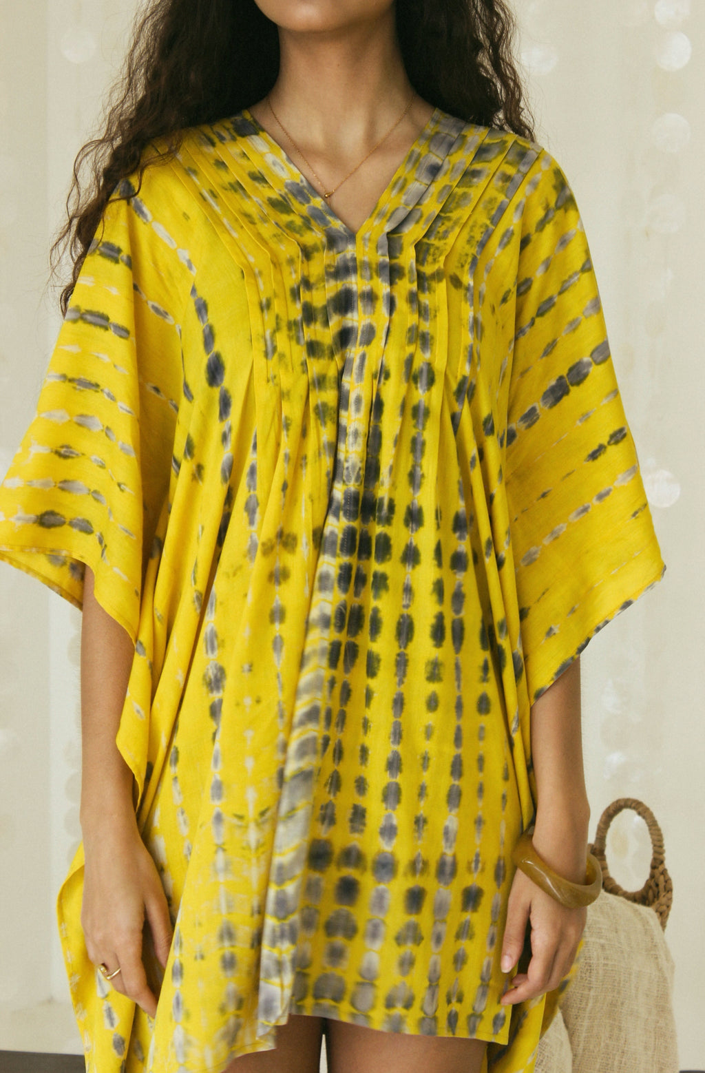 In detail view of a handmade yellow and black Bali tie-dye pattern featured on mini kaftan dress - Tulalara