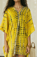 In detail view of a handmade yellow and black Bali tie-dye pattern featured on mini kaftan dress - Tulalara