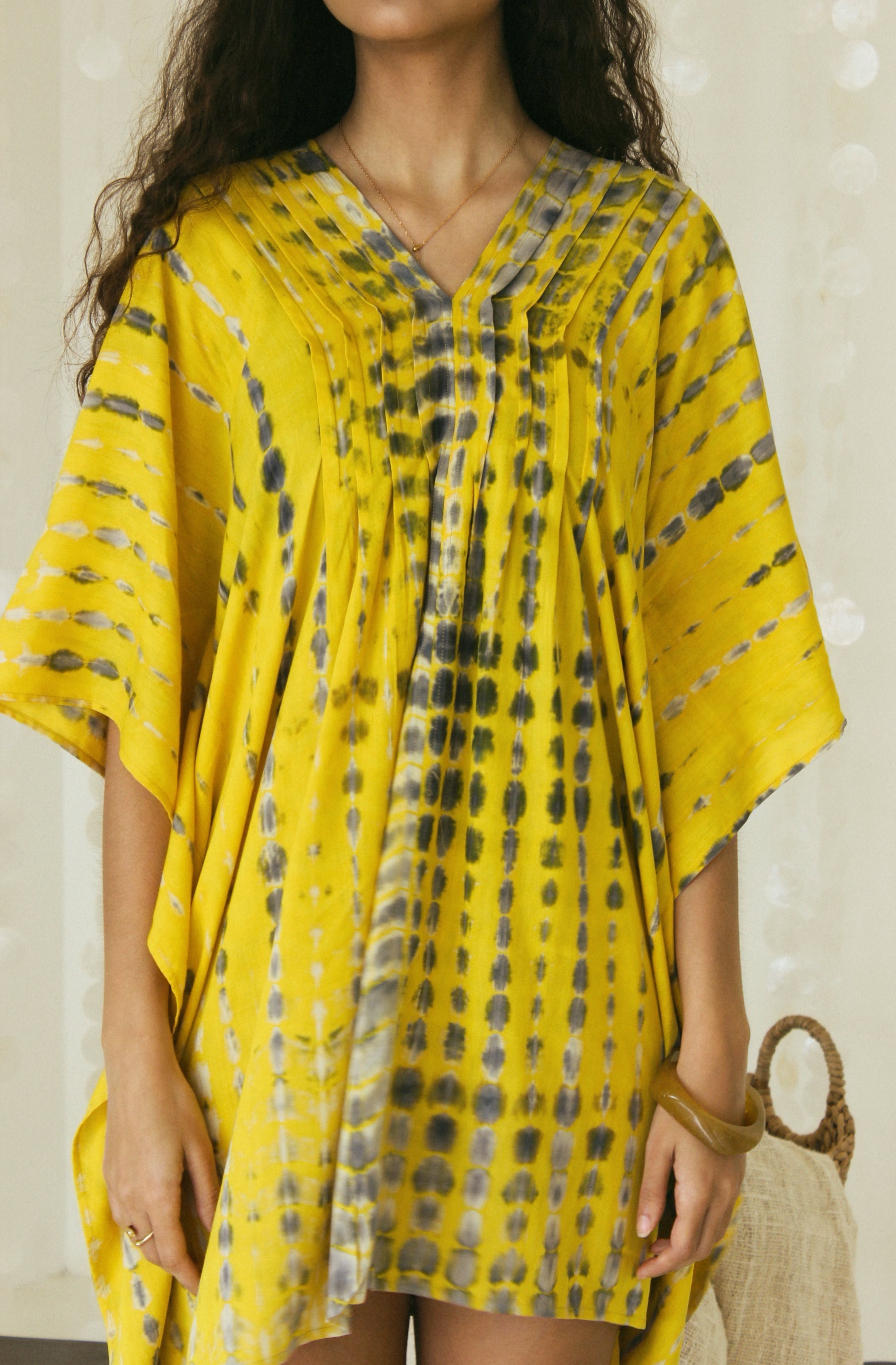 In detail view of a handmade yellow and black Bali tie-dye pattern featured on mini kaftan dress - Tulalara